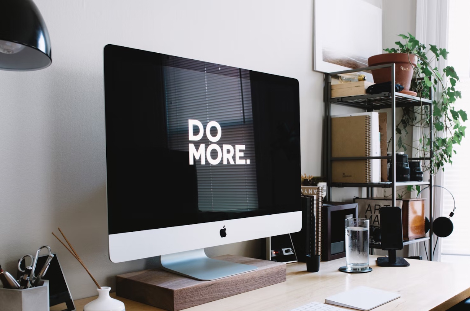 A Mac monitor on a fancy but conventional desk reads Do More